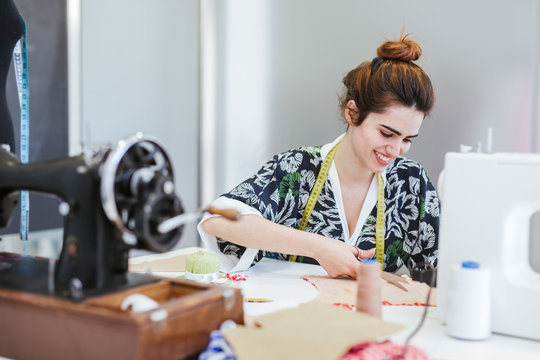 Teenage girl student practicing sewing on modern machine in cozy workshop