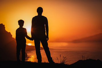 silhouette of father and son holding hands in sunset nature
