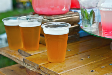 Beer in a plastic glass close-up. Alcoholic beverage at the festival. Bakal on a wooden board.