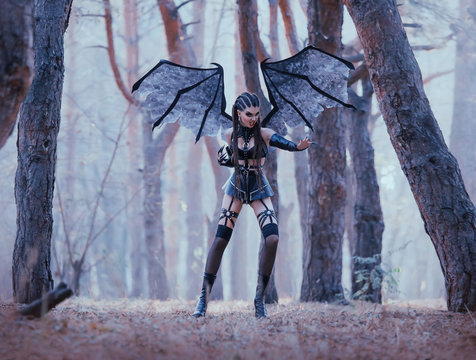 Wild Bat Protects Forest From Strangers, Sexy Passionate Demoness In Latex Leather Short Skirt And Stockings With Dark Makeup And Creative Hair, Aggressive Satan Woman With Long Claws And Wings