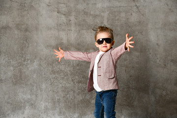 Image of cheerful excited little boy child standing isolated over concrete wall.