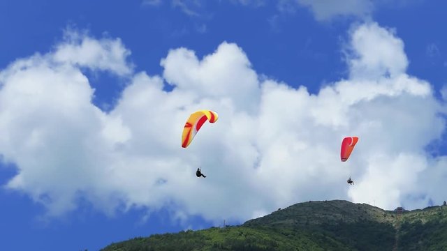 Paragliding over the mountains against clear blue sky. Summer afternoon. Extreme sport