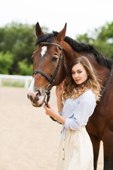 Portrait of young pretty cheerful woman with horse at summer 