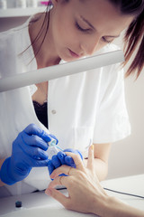 Female manicurist master applying nail polish in beauty salon