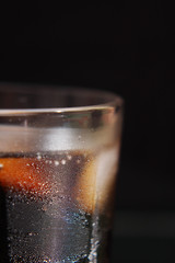 A steaming glass of cold thirst-quenching red-brown drink with ice cubes.