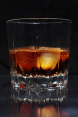 A steaming glass of cold thirst-quenching red-brown drink with ice cubes.