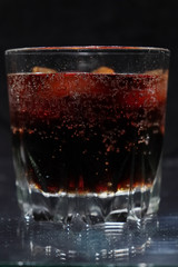 A steaming glass of cold thirst-quenching red-brown drink with ice cubes.