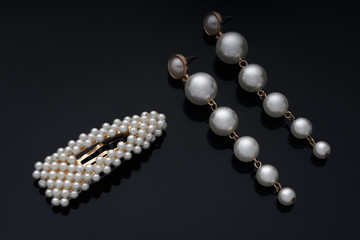 Pearl earrings and hairpin on black backgroun