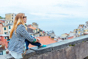 Fototapeta na wymiar Beautiful young woman enjoying the view of Manarola in the UNESCO World Heritage Site Cinque Terre, Liguria, Italy