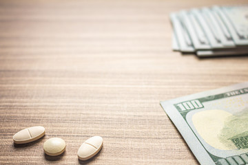 Fototapeta na wymiar Concept of cost of medicines. Several Pills on a brown table with bills.