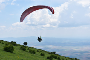 Young woman flying in the sky just launched her paraglider from the slopes of Stara Planina Mountain above the town of Sopot, Bulgaria