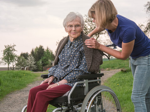 Young woman comforts sad senior in wheechair