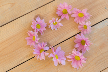 Beautiful flowers in heart shape on wooden background
