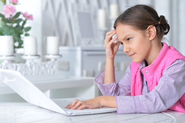 Portrait of cute little girl using modern laptop