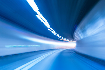 Speed motion in tunnel with curve. Abstract background in blue with motion blur and lights. Concept of speed and movement