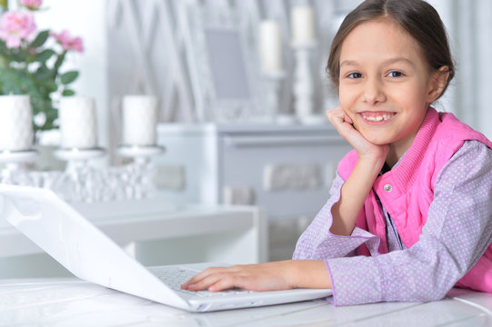Portrait of cute little girl using modern laptop
