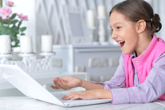 Portrait of cute little girl using modern laptop
