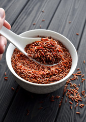 hand holdind a spoon with uncooked red rice