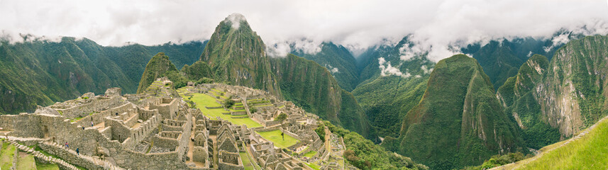 Top panoramic view of the upper town in Machu Picchu ancient city ruins with Huayna Picchu and the whole green valley on the background. Beautiful travel destination in the Sacred Valley, Peru