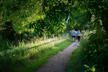 Fototapeta premium Couple with the same color clothes on their back walking on Grantham Canal,UK.