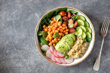 Healthy vegetarian salad with chickpeas, quinoa, cherry tomatoes, cucumber, radish, spinach, avocado and parsley. Ketogenic diet. Top view. 