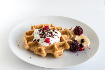 Delicious homemade oatmeal waffle with creamy natural yogurt, honey, banana, blueberry, raspberry and chopped chocolate