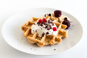 Delicious homemade oatmeal waffle with creamy natural yogurt, honey, banana, blueberry, raspberry and chopped chocolate