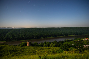 Obraz premium Ruined old castle tower at night on the river bank