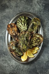 Closed oysters in nickel silver dish with lemon and champagne. Top view.  Copy space. 