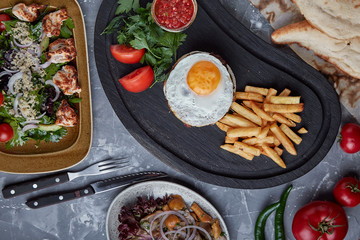 Beef steak with egg and salad from greens and vegetables. Wooden background, table setting, fine dining
