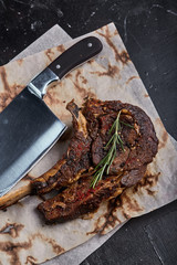 Tomahawk steak with vegetables and a knife on the table. Grilled meat with grilled vegetables and...