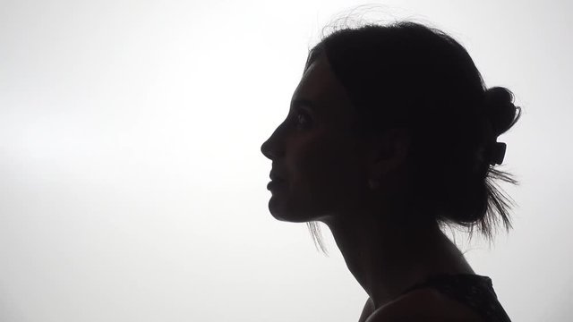 Silhouette of woman on white shot in studio, male hand gives strawberry to bite