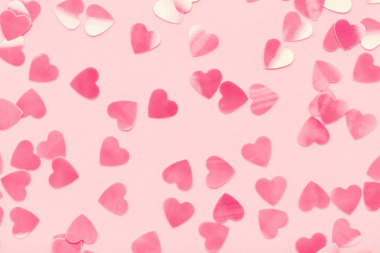 Heart shape confetti on pink pastel holiday background. Festive abstract backdrop, Valentine's Day, Love. Flat lay.