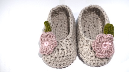 Cute baby beige colored shoes isolated on white background. Shoes made by crochet knitting.