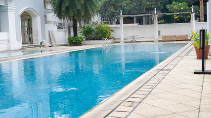 empty swimming pool with blue water in a residential area with green trees around it