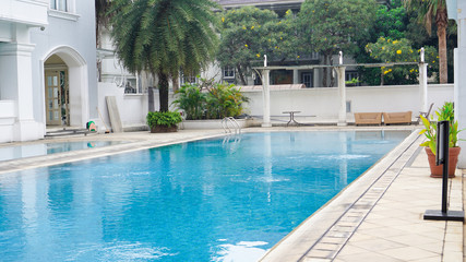 empty swimming pool with blue water in a residential area with green trees around it