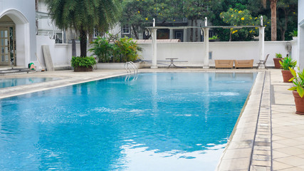 empty swimming pool with blue water in a residential area with green trees around it
