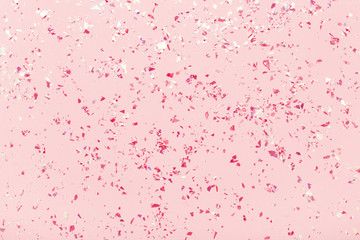 Glitter confetti. Mica Red sparkles on pink pastel background. Festive abstract backdrop. Flat lay.