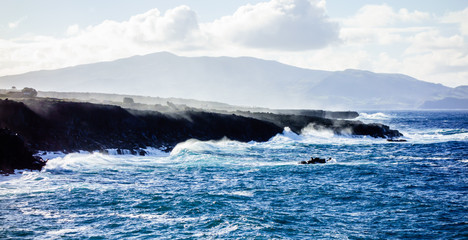 Ocean waves crashing on jagged cliffs.
