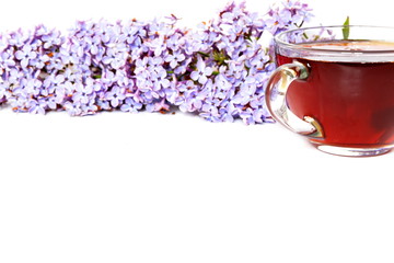 Obraz na płótnie Canvas Part with handle glass cup of black tea on white background decorated with flowers of purple lilac. Isolated
