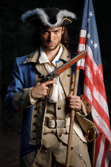 Portrait of man dressed as soldier of War of Independence United States aims from pistol with flag....