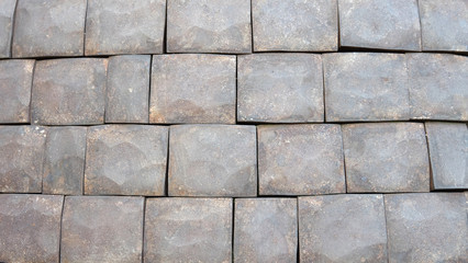 Square stone tiles with uneven surface and shapes arranged side by side into 4 rows.