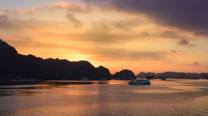 Naklejka na ściany i meble Tourist Junks in Halong Bay,Panoramic view of sunset in Halong Bay, Vietnam, Southeast Asia. Magical golden sunset.