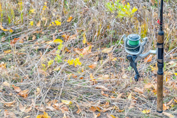 Fishing rod with a coil on the background of autumn grass. Selective focus