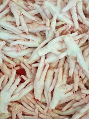 Top view of raw chicken feet as a background in the market for sale, fresh meat for cooking, vertical