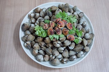 Soft focus of steamed cockles on white dish on wooden table, This food is most popular, Selective focus