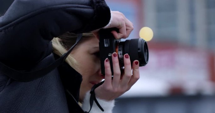 Authentic female photographer in leather jacket takes photo of city scape