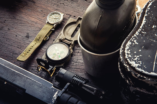 Military tactical equipment for the departure. Assortment of survival hiking gear on wooden background. Top view - vintage film grain filter effect styles