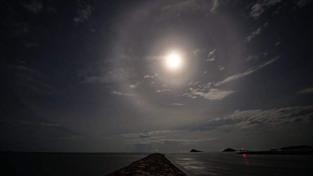 stunning beautiful big lunar ring and bright moon in little cloudy sky night floating over seascape stock photo