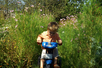 A little boy is learning to ride a bike.